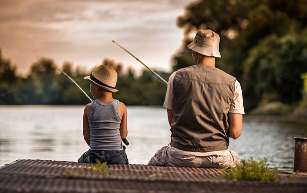 Rear view of a father and son fishing from the pier.